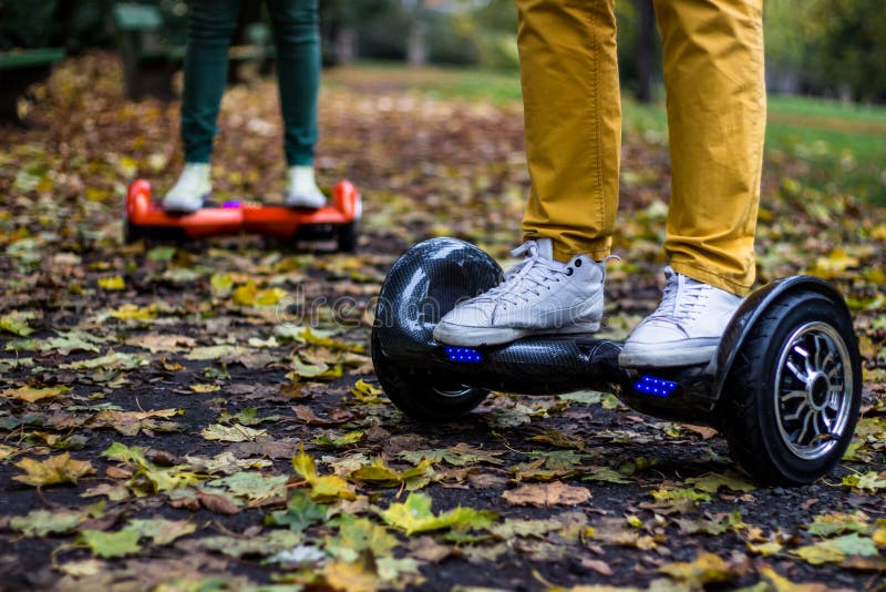 Two people are using hoverboards on the street. Two people are using hoverboards on the street