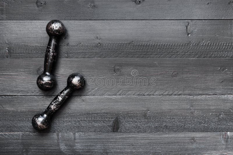 Dwa małego rocznika dumbbells na czarnej drewnianej podłoga zdjęcia royalty free Dwa małego rocznika dumbbells na czarnej drewnianej podłoga zdjęcia royalty free