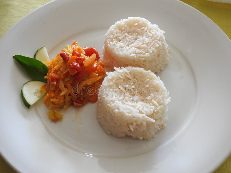 Two servings of rice, salad, cucumber and a tropical leaf. Creole cuisine. Seychelles. Two servings of rice, salad, cucumber and a tropical leaf. Creole cuisine. Seychelles