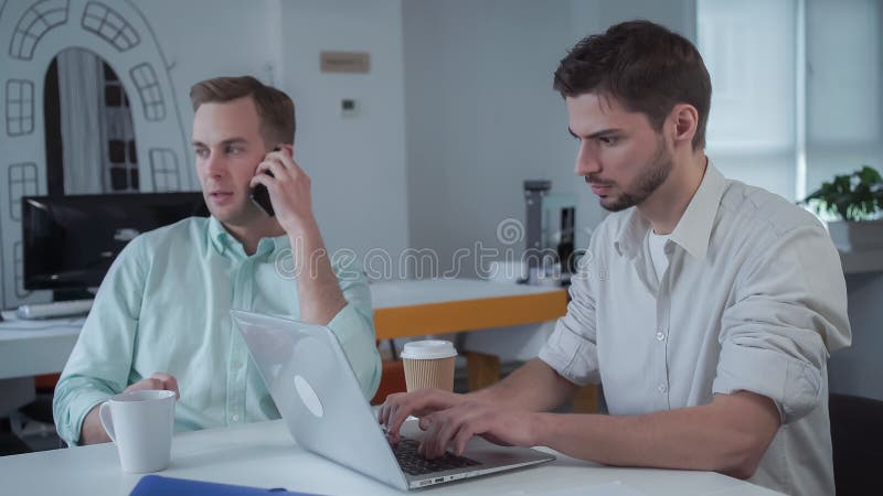 Dwa potomstw biznesmen pracuje przy nowożytnym biurem zdjęcie royalty free Dwa potomstw biznesmen pracuje przy nowożytnym biurem zdjęcie royalty free