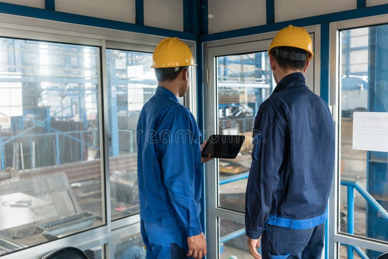Dwa pracownika jest ubranym ciężkich kapelusze podczas gdy używać pastylka peceta zdjęcia stock Dwa pracownika jest ubranym ciężkich kapelusze podczas gdy używać pastylka peceta zdjęcia stock