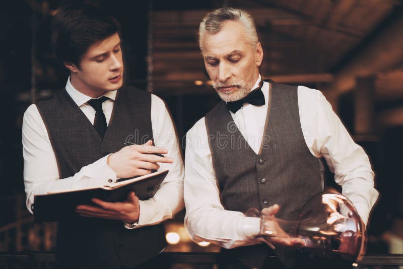 Dwa sommeliers smaku doświadczający wino Kelner nalewa wino od dekantatoru w szkło zdjęcie stock Dwa sommeliers smaku doświadczający wino Kelner nalewa wino od dekantatoru w szkło zdjęcie stock