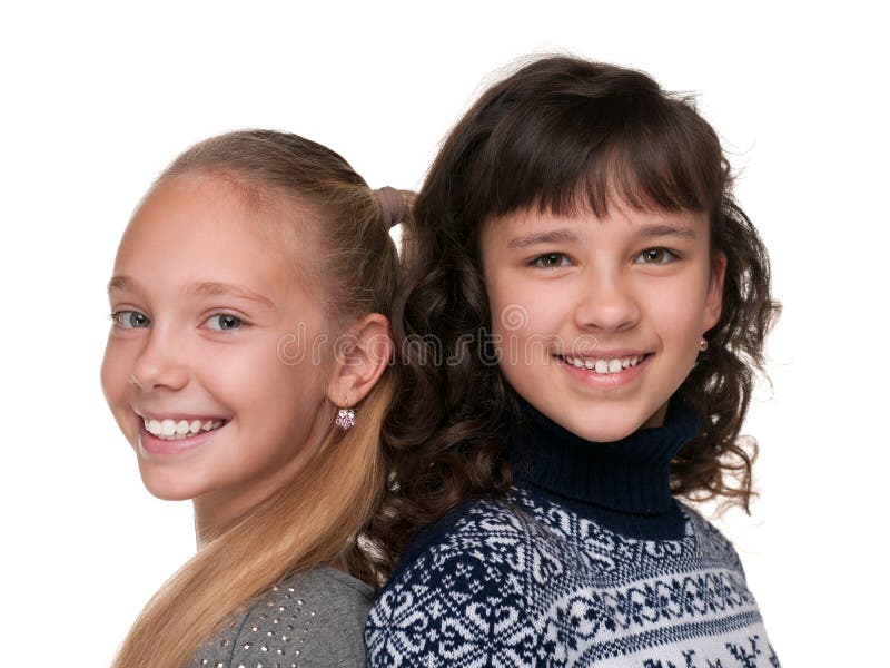 Two happy girls are standing together against the white background. Two happy girls are standing together against the white background