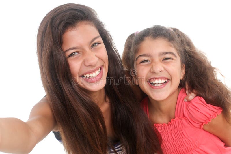 Two happy girls taking a self portrait on white background. Two happy girls taking a self portrait on white background