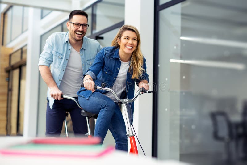 Dwa szczęśliwego coworkers jedzie bicykl w biurze wpólnie makin obraz royalty free Dwa szczęśliwego coworkers jedzie bicykl w biurze wpólnie makin obraz royalty free