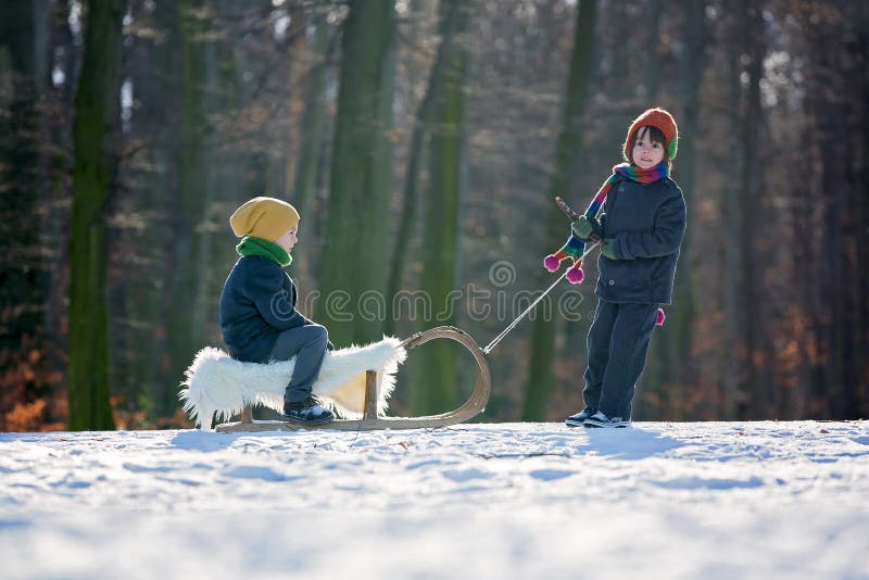 Dwa Szczęśliwego małego dziecka, chłopiec, bawić się outdoors w śnieżnym parku zdjęcia stock Dwa Szczęśliwego małego dziecka, chłopiec, bawić się outdoors w śnieżnym parku zdjęcia stock