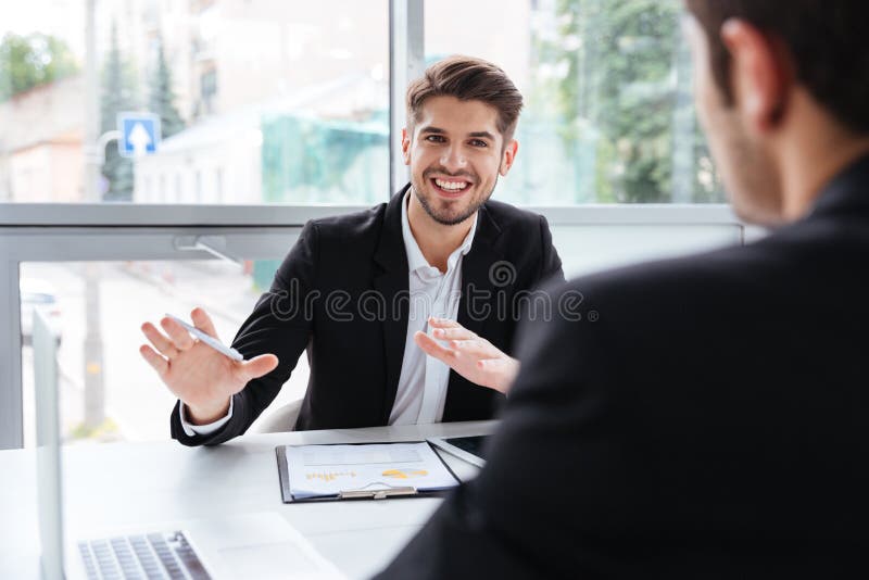 Dwa szczęśliwego młodego biznesmena siedzi i pracuje na biznesowym spotkaniu
