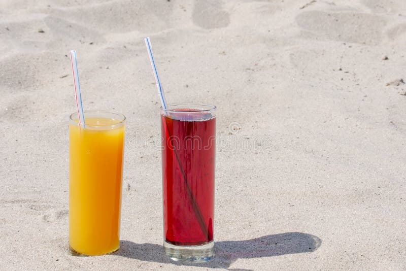 Dwa szklanego szkła z sokiem mango i wiśnia z tubules Piaskowata pla?a na letnim dniu zdjęcie stock Dwa szklanego szkła z sokiem mango i wiśnia z tubules Piaskowata pla?a na letnim dniu zdjęcie stock