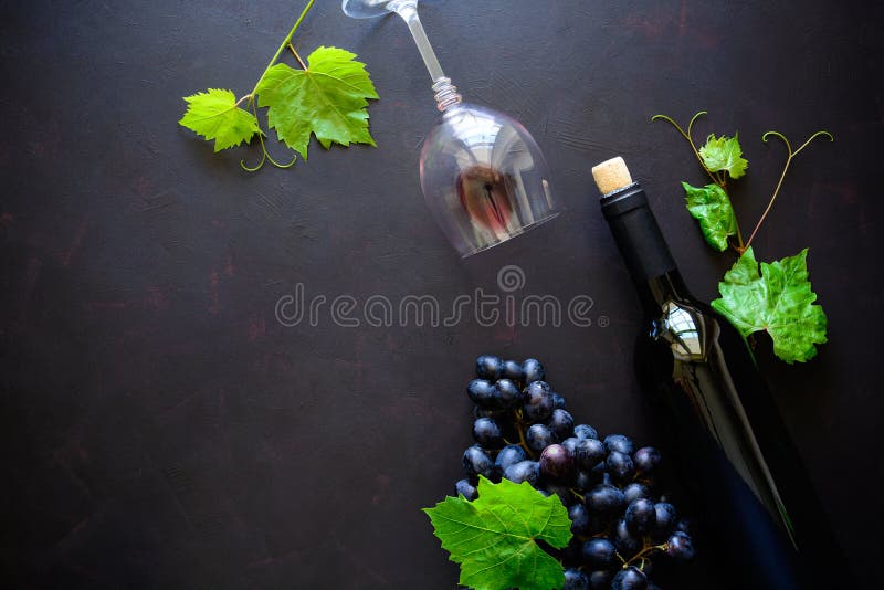 Two wineglasses with red wine, bottle and grape leaves lying on dark wooden background. Top view. Flat lay. Copy space. Two wineglasses with red wine, bottle and grape leaves lying on dark wooden background. Top view. Flat lay. Copy space