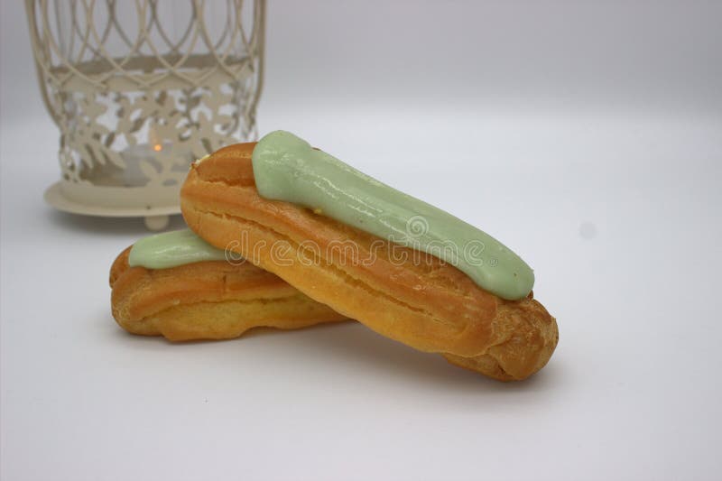 Dwa Wy?mienicie Pistacjowego Eclairs Na Bia?ym tle W tle, Tam Jest metalu Candlestick zdjęcie royalty free Dwa Wy?mienicie Pistacjowego Eclairs Na Bia?ym tle W tle, Tam Jest metalu Candlestick zdjęcie royalty free