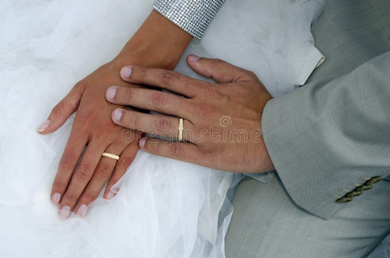 Dwa złocistej obrączki ślubnej na brides ślubnej sukni zdjęcie stock Dwa złocistej obrączki ślubnej na brides ślubnej sukni zdjęcie stock