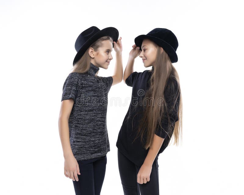 Dwa ślicznej nastoletniej dziewczyny uczennicy jest ubranym turtleneck pulowery, cajgi, kapelusze, uśmiechnięty taniec i spojrzen zdjęcie stock Dwa ślicznej nastoletniej dziewczyny uczennicy jest ubranym turtleneck pulowery, cajgi, kapelusze, uśmiechnięty taniec i spojrzen zdjęcie stock