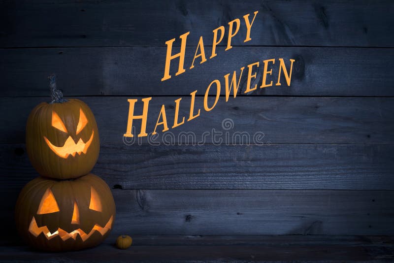Dwa Ślicznej Zaświecającej bani z Szczęśliwym Halloween Pisać na zmroku - błękitny Nieociosany drewno deski tło fotografia royalty free Dwa Ślicznej Zaświecającej bani z Szczęśliwym Halloween Pisać na zmroku - błękitny Nieociosany drewno deski tło fotografia royalty free