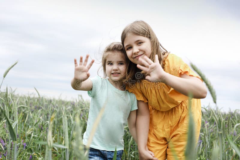 Two little girls hugging each other on a summer field. Happy sisters on summer meadow. Two little girls hugging each other on a summer field. Happy sisters on summer meadow
