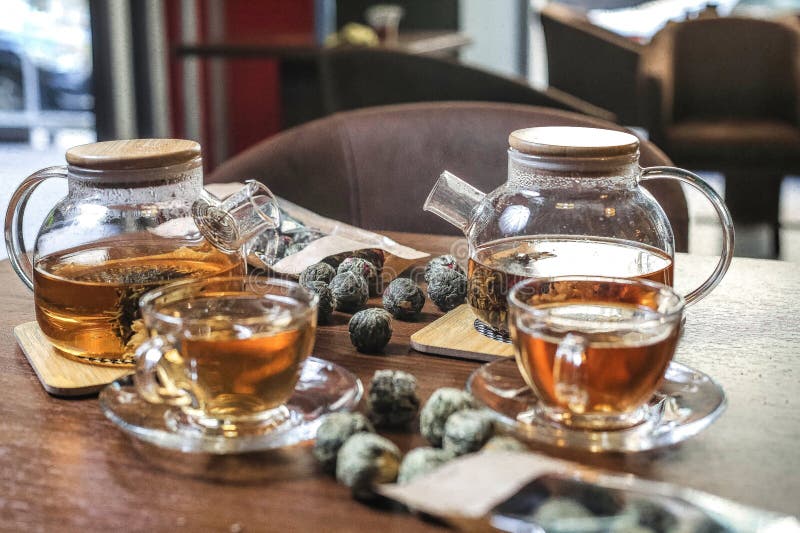 Two cups of tea, one with a teabag and steam rising, sitting on a wooden table. Two cups of tea, one with a teabag and steam rising, sitting on a wooden table.