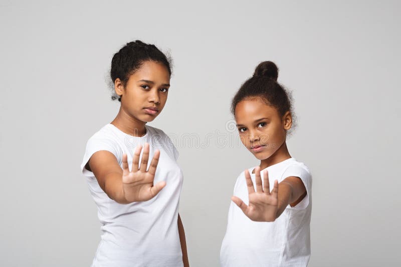 Beautiful african teenaged girls showing no sign over grey studio background. Beautiful african teenaged girls showing no sign over grey studio background