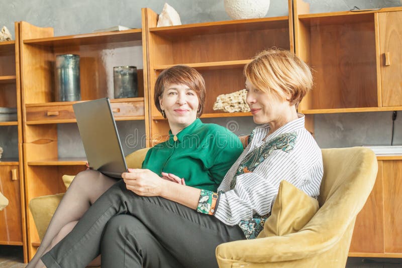 Two friendly mature women with laptop at home. Two friendly mature women with laptop at home.