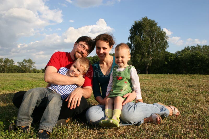 Family with two children sit on meadow and trees 2. Family with two children sit on meadow and trees 2