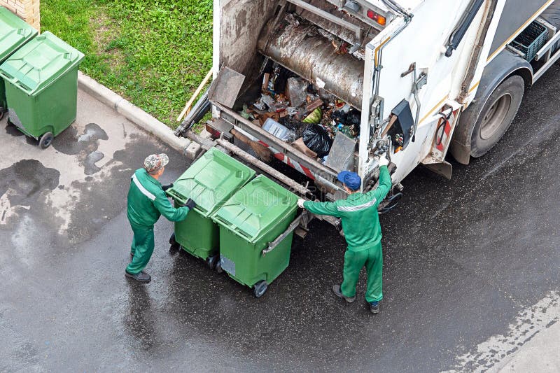Dwóch pracowników załadujących odpady z gospodarstw domowych do ciężarówek do zbierania odpadów