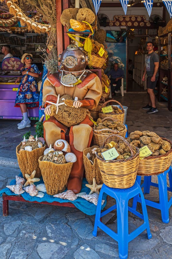 SYMI, GREECE - JULY 3,02022: Vintage diving suit used as a tourist attraction in front of a natural sponge shop in Symi town, Symi island, along with a collection of samples from the store`s products. SYMI, GREECE - JULY 3,02022: Vintage diving suit used as a tourist attraction in front of a natural sponge shop in Symi town, Symi island, along with a collection of samples from the store`s products