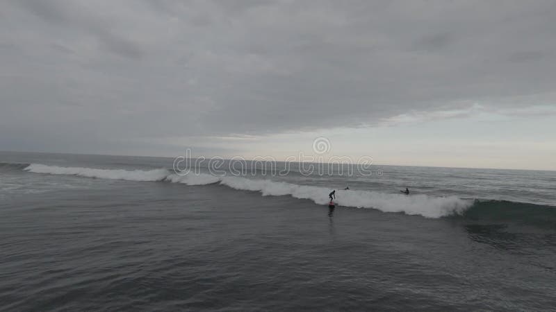 Dynamische Surfer warten auf ihre Wellen draußen im Wasser, wenn ein Surfer eine Welle springt. Bildmaterial. Meerblick