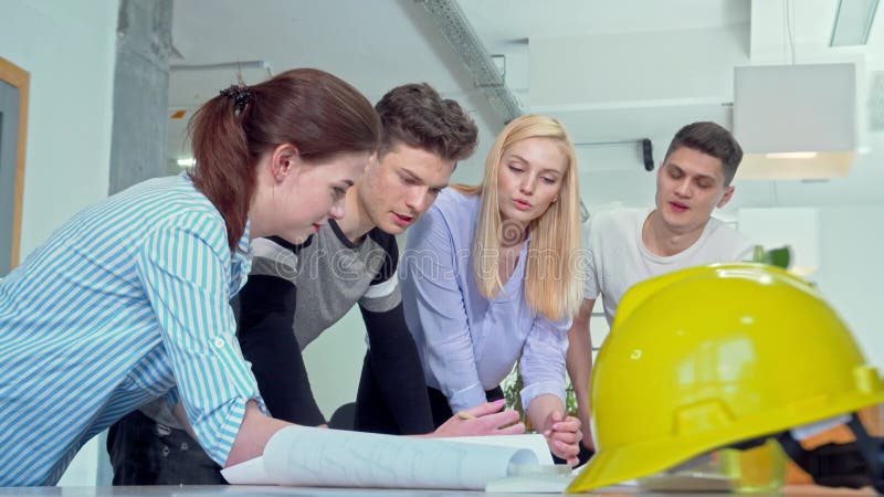 Dynamisk grupp av unga ingenjörer som engagerat diskuterar arkitektoniska planer stock video