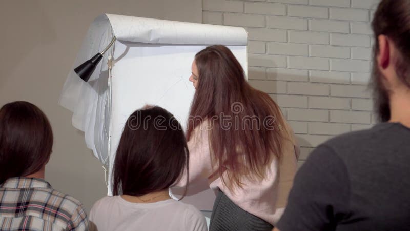 Dynamisk ung företagare som med stor entusiasm presenterar ett flipdiagram under en konferens arkivfilmer