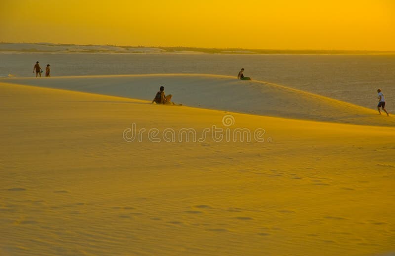 Scenic view of people on yellow sand dunes with sea in background, Jericoacoara National Park, Ceara, Brazil. Scenic view of people on yellow sand dunes with sea in background, Jericoacoara National Park, Ceara, Brazil