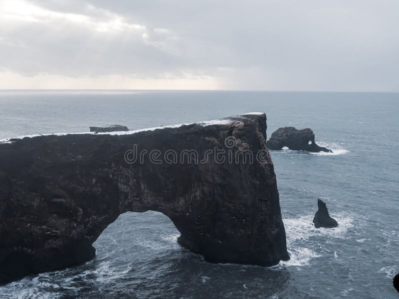 Dyrhalaey Arch Islandia dramatyczne formowanie się skał przybrzeżnych w północnym Oceanie Atlantyckim. Śnieżny łuk skalny o wytrzy fotografia royalty free