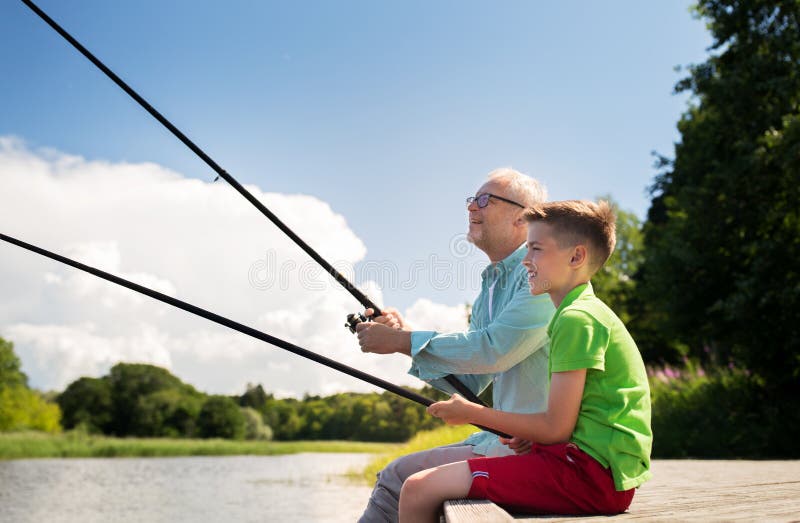 Family, generation, summer holidays and people concept - happy grandfather and grandson with fishing rods on river berth. Family, generation, summer holidays and people concept - happy grandfather and grandson with fishing rods on river berth