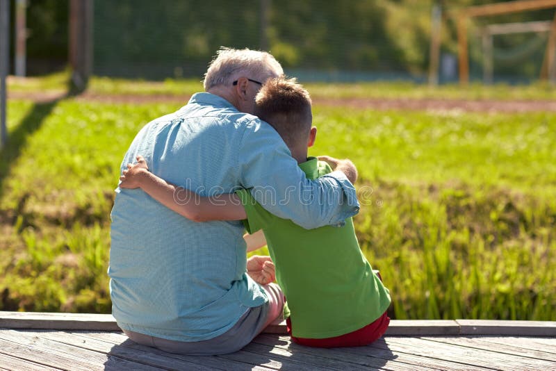 Family, generation, relations and people concept - happy grandfather and grandson hugging on berth. Family, generation, relations and people concept - happy grandfather and grandson hugging on berth