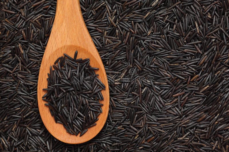 Wild rice in a wooden spoon on wild rice background. Close-up. Wild rice in a wooden spoon on wild rice background. Close-up.