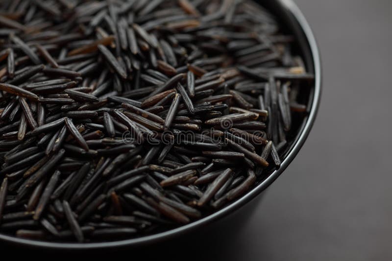 Wild rice in a black bowl on black background. Close-up. Wild rice in a black bowl on black background. Close-up.