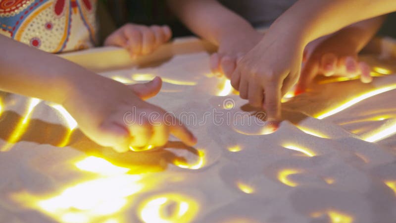 Dzieci rysują z palcami w piasku na przyrząd powierzchni
