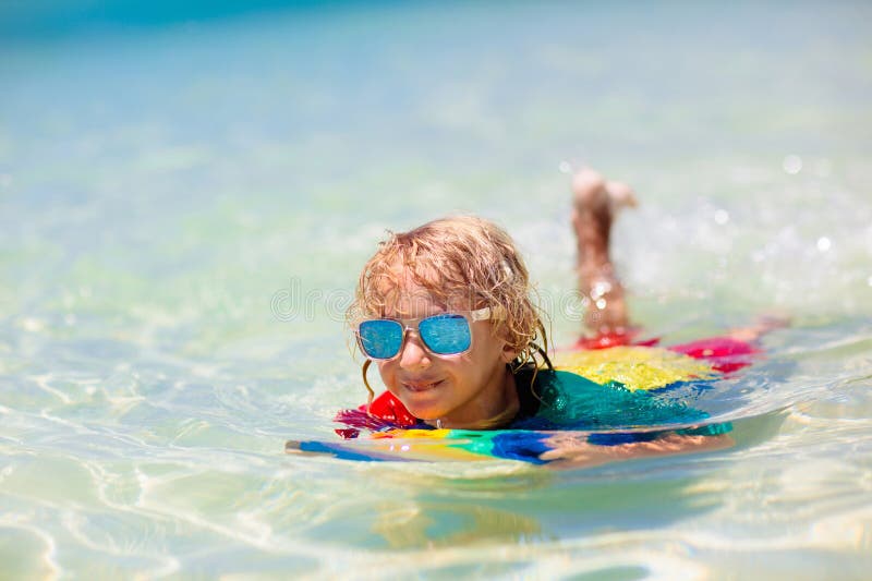 Dzieci surfują po tropikalnej plaży. wakacje z dzieckiem zdjęcia stock
