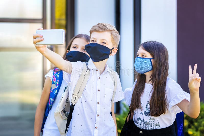 School children wearing protective face masks taking selfie at school reopening, New normal concept with happy kids having fun after classes were open and corona virus lockdown and quarantine ended. School children wearing protective face masks taking selfie at school reopening, New normal concept with happy kids having fun after classes were open and corona virus lockdown and quarantine ended