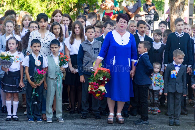 Dzieci z bukietami kwiaty zapisywali się w pierwszej klasie przy szkołą z nauczycielami i szkoła średnia uczniami przy solennym o fotografia stock Dzieci z bukietami kwiaty zapisywali się w pierwszej klasie przy szkołą z nauczycielami i szkoła średnia uczniami przy solennym o fotografia stock
