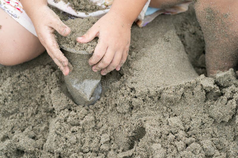 Dzieciak sztuk i chwytów piasek w plastikowej filiżance na plaży