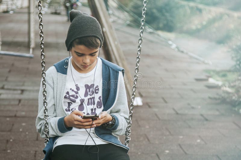 Dzieciak używa smartphone na huśtawce obrazy stock Dzieciak używa smartphone na huśtawce obrazy stock