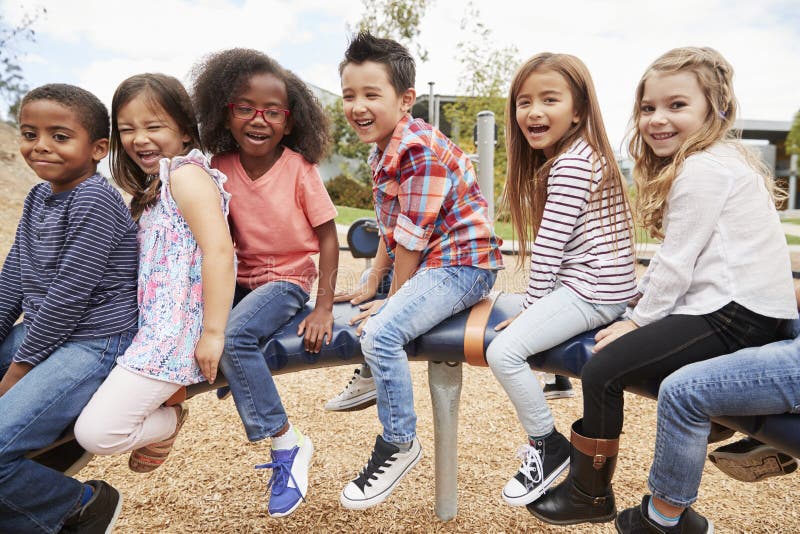 Kids sitting on a carousel in their schoolyard, side view. Kids sitting on a carousel in their schoolyard, side view