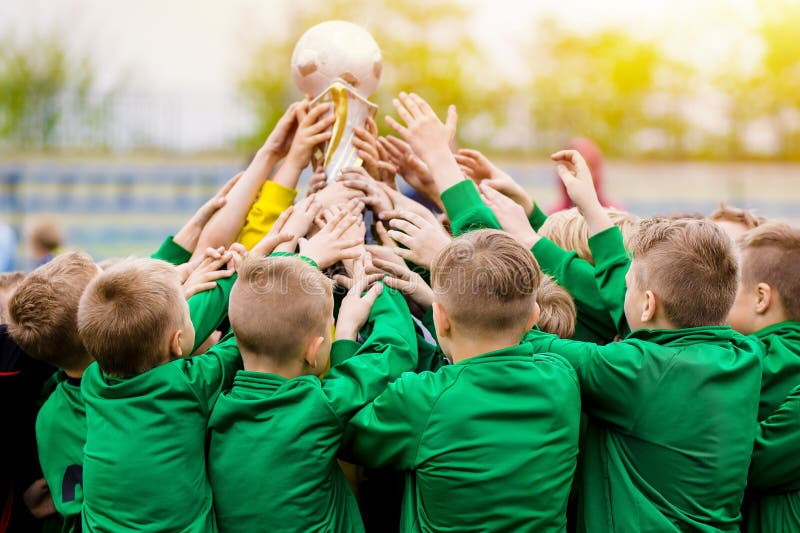 Dzieciaki Świętuje piłki nożnej zwycięstwo Młodzi gracze futbolu Trzyma trofeum zdjęcie royalty free Dzieciaki Świętuje piłki nożnej zwycięstwo Młodzi gracze futbolu Trzyma trofeum zdjęcie royalty free