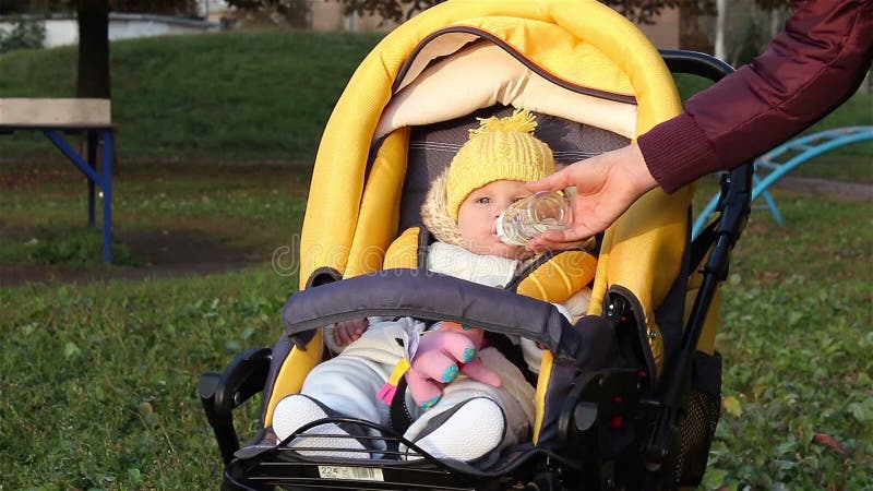 Dziecka obsiadanie w dziecko frachcie, matka daje butelce z wodą