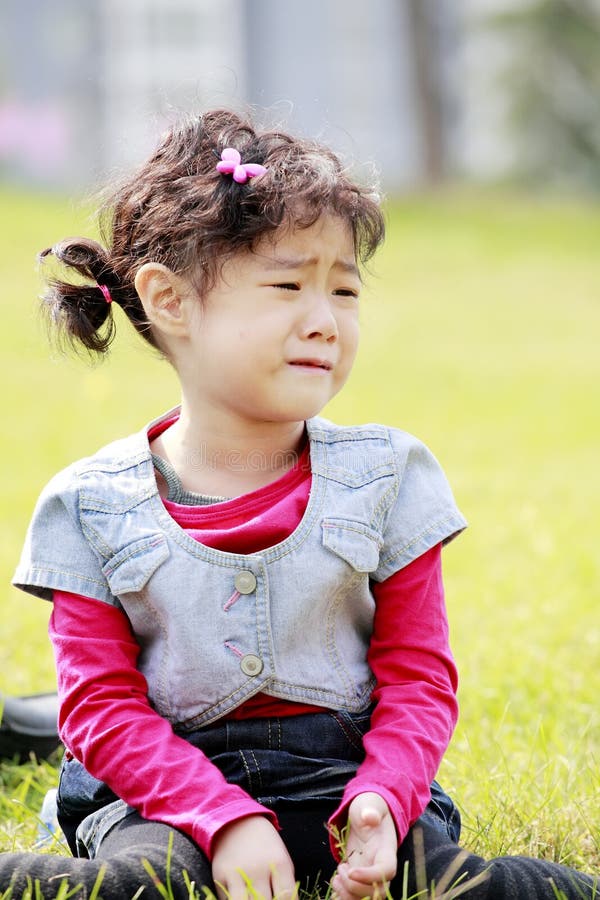 Cute Asian child crying on the grass. Cute Asian child crying on the grass.