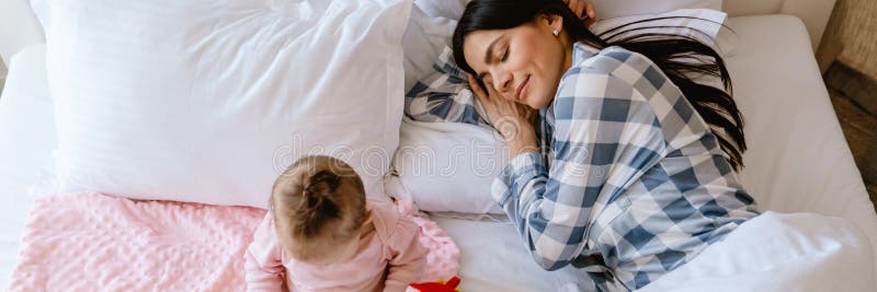 Dziecko bawiące się zabawkami, podczas gdy jej matka śpi źle w domu