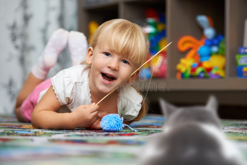 Pet perspective. Child playing with a cat on the floor in the children`s room. Pet perspective. Child playing with a cat on the floor in the children`s room.