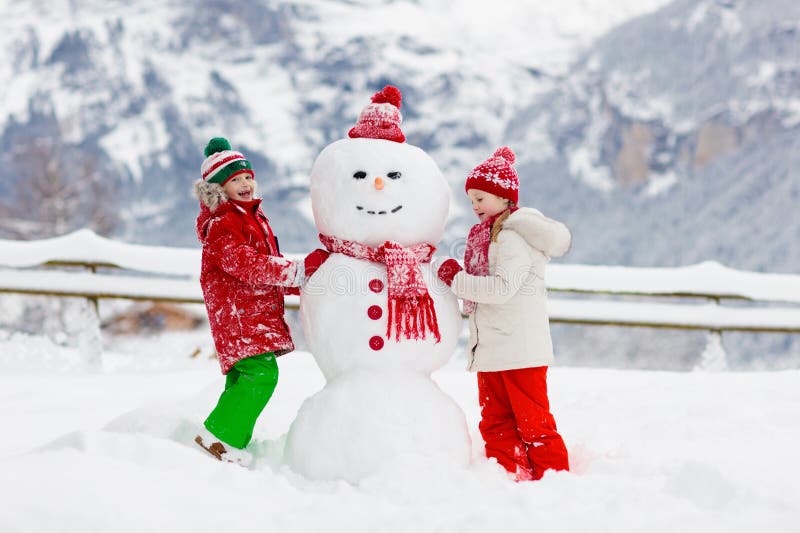 Dziecko budynku bałwan Dzieciak budowy śnieżny mężczyzna Chłopiec i dziewczyna bawić się outdoors na śnieżnym zima dniu