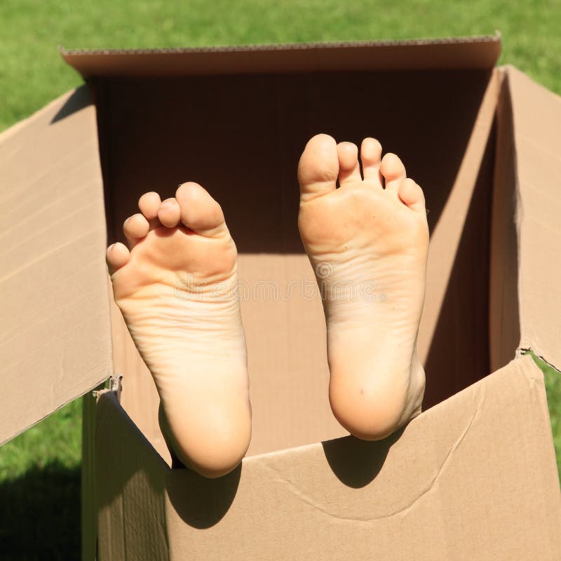 Child bare feet of a little girl sticking from a paper box. Child bare feet of a little girl sticking from a paper box