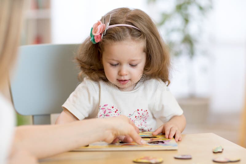 Dziecko dzieciak bawić się z łamigłówką kształtuje na depresja stole w dziecko pokoju w pepinierze lub preschool obraz stock Dziecko dzieciak bawić się z łamigłówką kształtuje na depresja stole w dziecko pokoju w pepinierze lub preschool obraz stock