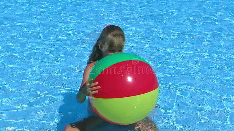 Dziecko dziewczyna bawić się z plażową piłką w błękitne wody