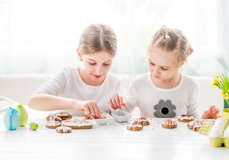 Dziecko dziewczyna dekoruje Wielkanocnych ciastka zdjęcie stock Dziecko dziewczyna dekoruje Wielkanocnych ciastka zdjęcie stock